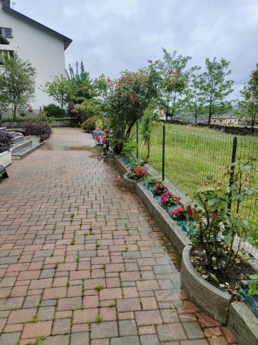 a brick walkway with flowers and a fence at House curti in Sorico