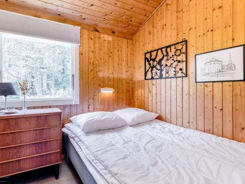 sypialnia z łóżkiem w drewnianej ścianie w obiekcie Holiday home Strandby XIII w mieście Strandby