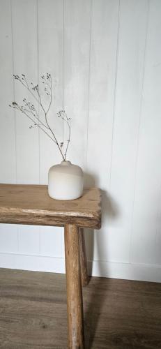 a white vase sitting on top of a wooden table at Les Cocons d AleXan Le Chalet balnéo aromathérapie in Quinssaines