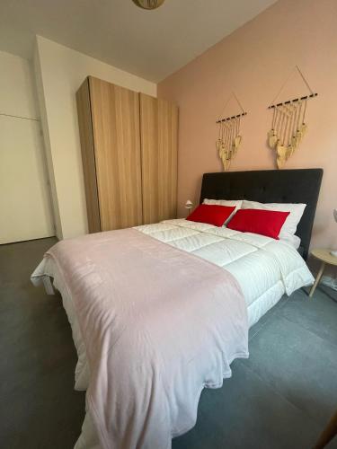 une chambre avec un grand lit blanc avec des oreillers rouges dans l'établissement Le contemporain - Golfe Juan - 5 min des plages - 10 min de Cannes!, à Vallauris