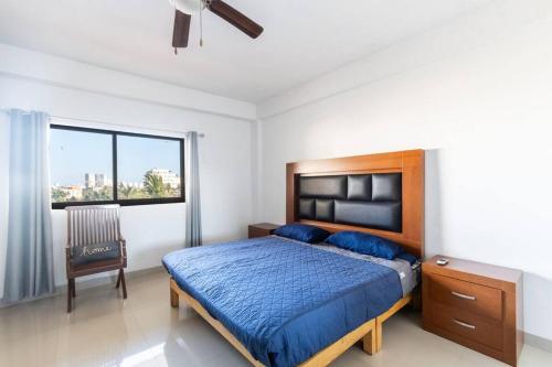 Un dormitorio con una cama y una silla y una ventana. en Marina del rey 505 a pie de playa, en Mazatlán