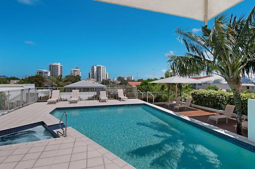 a swimming pool with chairs and a palm tree at Rovera Apartments in Maroochydore