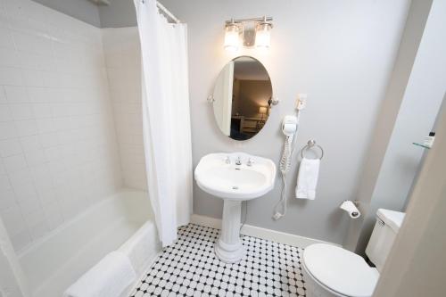 a white bathroom with a sink and a mirror at The New London Inn in New London