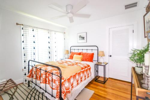 a bedroom with a bed with orange pillows and a fan at Bohemian Bungalow in St Augustine! in St. Augustine