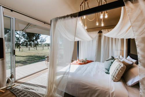 1 dormitorio con cama con dosel y puerta corredera de cristal en Parklands Resort en Mudgee