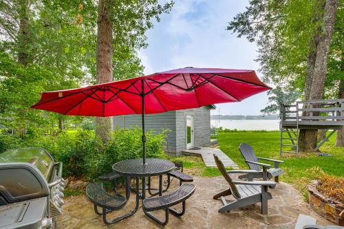 a table and chairs with a red umbrella at Waterfront Yantis Retreat with Deck and Zipline! in Yantis