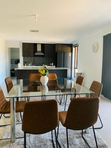 a dining room with a glass table and chairs at Nevid Family Home in Merbein South