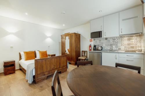 a bedroom with a bed and a kitchen with a table at Casa de Belmonte in Castelo de Paiva