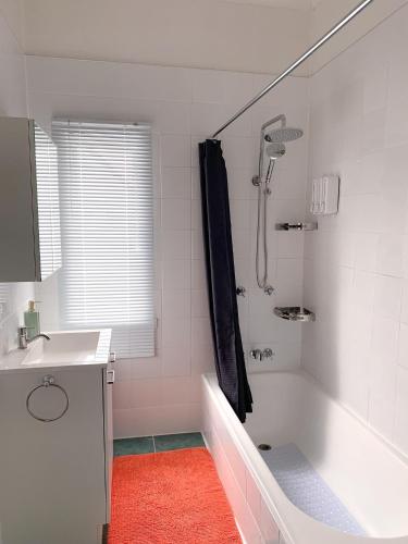 a white bathroom with a tub and a sink at West End Studio 5 in Brisbane