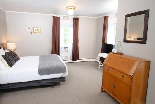 a bedroom with a bed and a dresser and a mirror at The New London Inn in New London