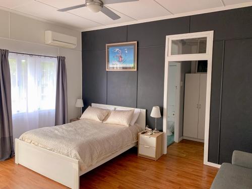 a bedroom with a white bed and a gray wall at West End Studio 5 in Brisbane