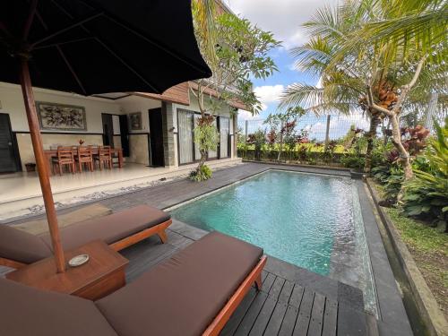 einen Pool in einer Villa mit Sonnenschirm in der Unterkunft Bayad anyar - Ubud Bali in Ubud