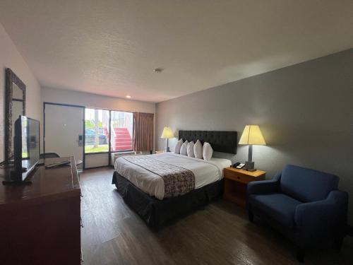 a hotel room with a bed and a blue chair at Garden Inn Homestead/Everglades/Gateway to Keys in Homestead