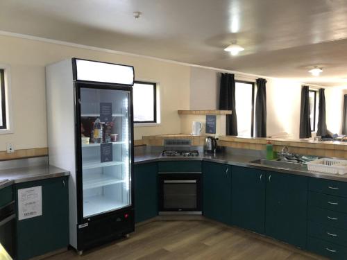 a kitchen with green cabinets and a glass refrigerator at Pinewood Lodge in Queenstown