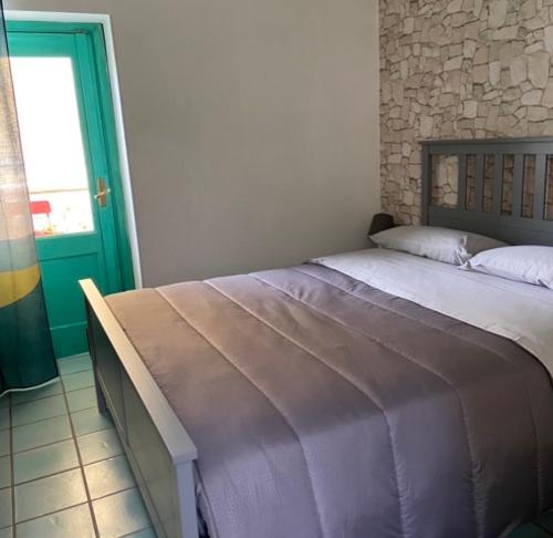 a bed in a bedroom with a green door at Caieta: la casa nella roccia in Gaeta
