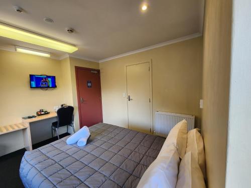 a bedroom with a bed with a blue pillow on it at Pinewood Lodge in Queenstown