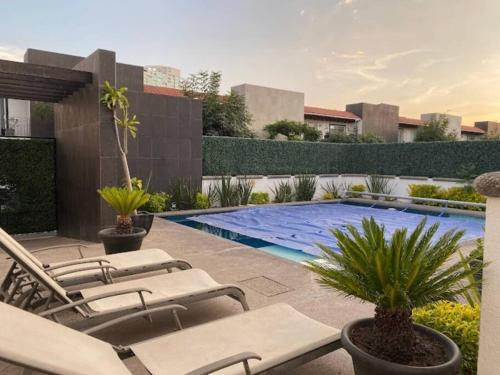 a patio with lounge chairs and a swimming pool at Residencial Quinta las Acacias, Santa Fe, Juriquilla in Juriquilla