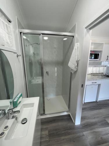 a white bathroom with a shower and a sink at Ellis Beach Oceanfront Holiday Park in Palm Cove