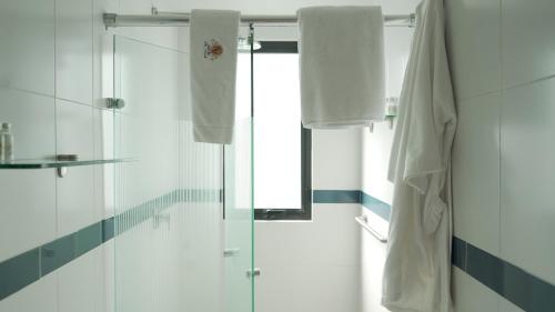 a bathroom with a shower and white towels at Suites del Valle in Mexico City