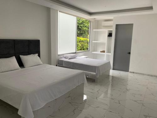 a white bedroom with two beds and a window at Finca los mangos in La Mesa