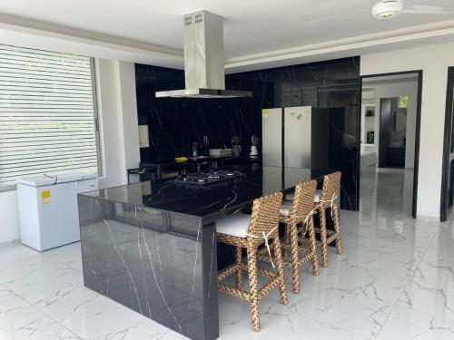 a kitchen with a black counter and stools at Finca los mangos in La Mesa