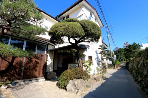 a house with a tree on the side of it at 城下町に佇む癒しの宿 旅館 大政 in Karatsu