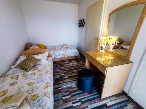 a bedroom with two beds and a desk and a mirror at Apartman Damir in Sumartin