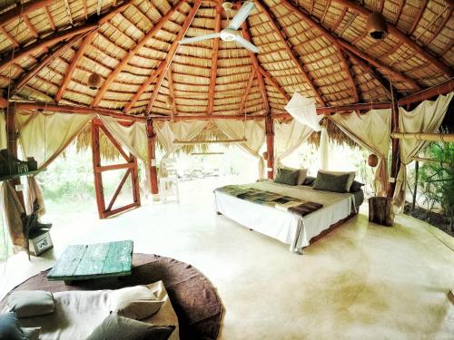 Dream Glamping Jungle Bohio في لاس تاريناس: غرفة نوم في خيمة مع سرير وأريكة