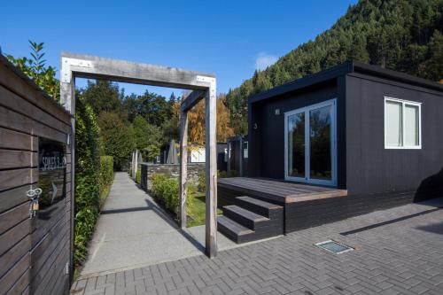 a black tiny house with a porch and stairs at Pinewood Lodge in Queenstown