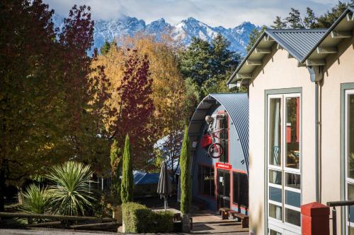 a building with trees and mountains in the background at Pinewood Lodge in Queenstown