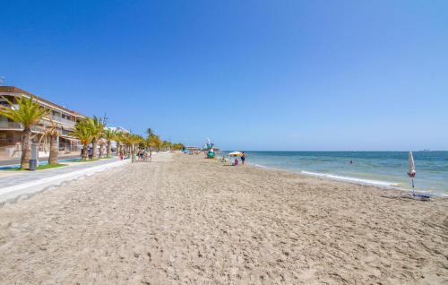 a beach with palm trees and people on it at Cozy Home In San Pedro Del Pinatar in San Pedro del Pinatar