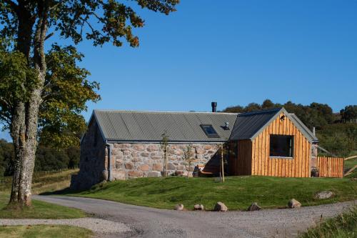 a stone and wood cabin with a gambrel roof at The Stable Bothy in Rogart