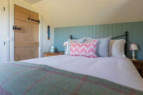 a bedroom with a large bed with pink and purple pillows at The Stable Bothy in Rogart