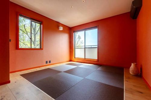 an empty room with orange walls and two windows at Villa Secca in Futo