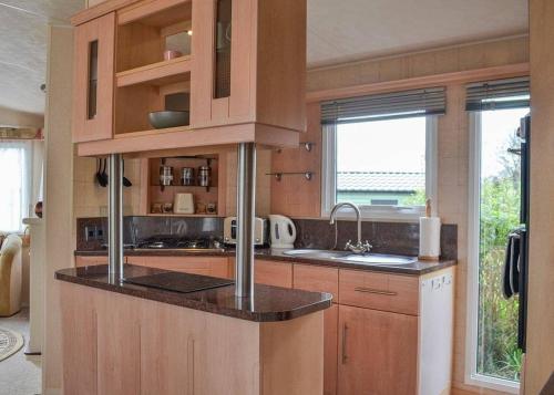 a kitchen with wooden cabinets and a counter top at Tan-y-fron Holiday Park in Dolgellau