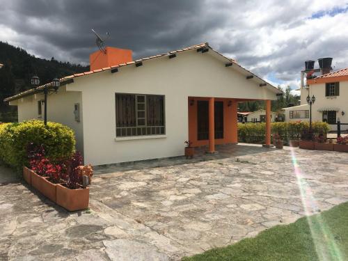 a white house with a stone patio in front of it at Casa Hotel Descanso Real in Paipa