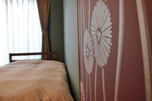 a bedroom with a wall with a flower design on it at 料理旅館ゆり野 in Wajiki