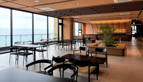 un ristorante con tavoli, sedie e ampie finestre di Ramada by Wyndham Gangwon Sokcho a Sokcho