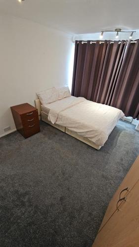 um quarto com uma cama, uma cómoda e uma janela em Sariyu space em Dagenham