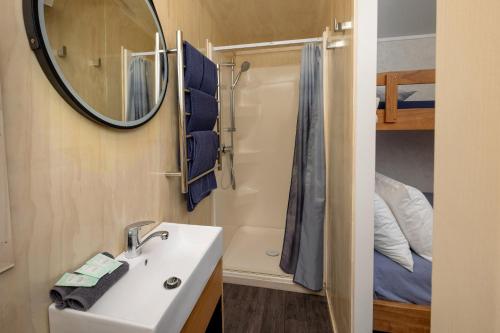 a bathroom with a sink and a mirror and a bed at Napier Beach Top 10 Holiday Park & Motels in Napier