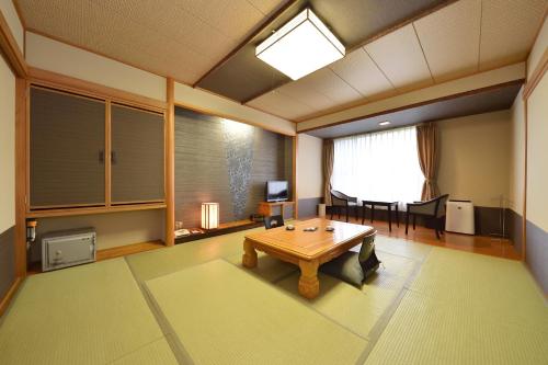 a living room with a table and a dining room at Biei Shirogane Onsen AONOBI YUYU in Biei
