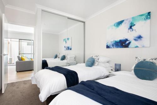 een slaapkamer met 3 bedden en een woonkamer bij Bright Trendy 2bdrm Apt - Walk to River & Shops in Perth