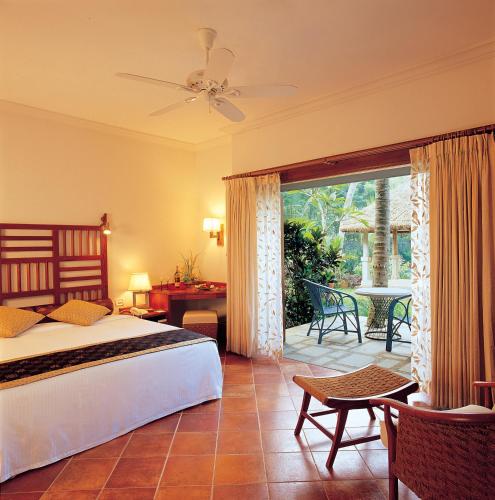 a bedroom with a bed and a patio with a table at Taj Green Cove Resort and Spa Kovalam in Kovalam