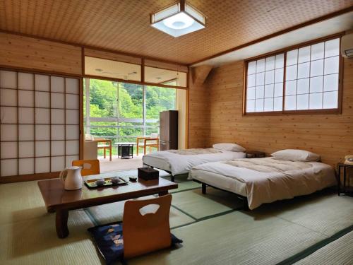 a room with two beds and a table and windows at 大和屋ホテルいろは in Nikko