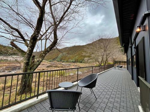 a balcony with two chairs and a table and a tree at 料理旅館ゆり野 in Wajiki