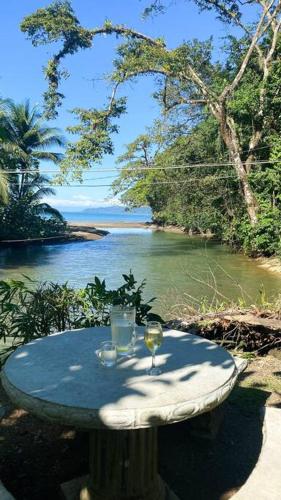 a table with two wine glasses on it next to a river at Azul Vista Drake Bay-AC-Full Kitchen in Drake