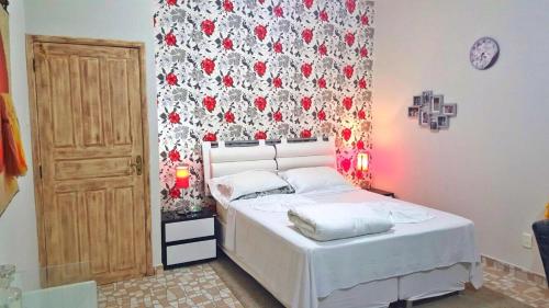 a bedroom with a white bed and a floral wall at Pousada Recanto do Sal in Salinópolis