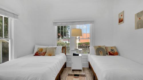 two beds in a room with white walls and windows at Beaches, Parks, Downtown, Trail, Breweries, Bikes, Gameroom in Palm Harbor