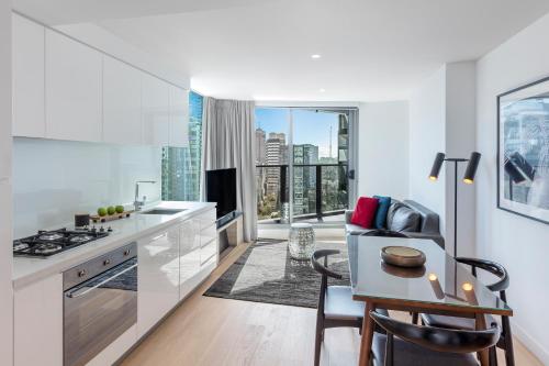a kitchen with white cabinets and a table with chairs at Imagine Marco in Melbourne