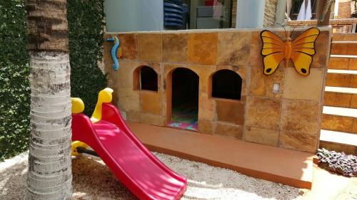 a pretend play area with a slide and a butterfly house at Pousada Recanto do Sal in Salinópolis